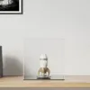 A white and gold rocket figurine displayed inside a clear acrylic cube on a wooden shelf. Náhľad obrázku produktu