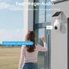 A woman is at her front door, interacting with a security camera that has a solar panel. Produktbild-Vorschau