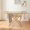 A wooden drying rack with clothes hanging on it, in a room with artwork on the wall. Anteprima dell’immagine prodotto