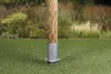 A wooden post is secured in the ground by a metal base, with a grassy lawn and foliage in the background. Produktbild-Vorschau