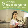 A woman is smiling while holding a mixing bowl in a kitchen. Produktbild-Vorschau
