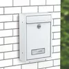 A white mailbox mounted on a white brick wall. Produktbild-Vorschau