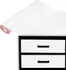 A roll of white vinyl wrap partially unfurled over the top of a black and white two-drawer cabinet. Produktbild-Vorschau