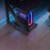 A gaming computer tower with RGB lighting sits on a stand under a desk, with ambient blue and pink lighting reflecting on the wooden floor. Podgląd zdjęcia produktu