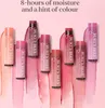 A collection of Burt's Bees tinted lip balms in various shades, arranged on a pink, brush-stroke-like background. Náhled obrázku produktu
