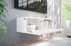 A white floating media console with its front open, revealing books inside. A large TV is mounted on a gray wall above it. Voir les images du produit