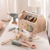 A wooden toy toolbox and accessories are laid out on a white surface. Produktbild-Vorschau