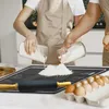 Two people are baking, pouring flour onto a baking mat. Voir les images du produit
