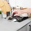 A hand is placing a glass lid on a stovetop. Podgląd zdjęcia produktu