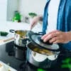 A person is cooking in a kitchen, using pots on a stovetop. Podgląd zdjęcia produktu