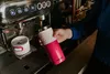A person is holding a pink thermos under an espresso machine. Náhled obrázku produktu
