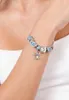 A close-up shot of a person's arm wearing a charm bracelet with various charms, including a Stitch charm. Podgląd zdjęcia produktu