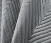 A close-up view of a gray quilted blanket with a chevron pattern. Podgląd zdjęcia produktu