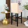 A beige bar stool cover is shown on a bar stool, with a side table and flowers in the background. Produktbild-Vorschau