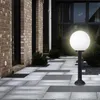 A modern outdoor pathway with a globe-shaped garden lamp. Voir les images du produit