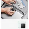 Hands placing a compact black wall charger into an open suitcase next to a laptop and a plane ticket. Anteprima dell’immagine prodotto