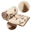 A rolled-up and unrolled wool blanket with a leaf pattern, shown with close-up details of the texture and edging. Produktbild-Vorschau