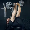 A man is lying on a bench and lifting a barbell. Produktbild-Vorschau