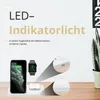 A white wireless charging station with a phone, smartwatch, and earbuds placed on it, set against a light gray and white background with some decorative elements and text. Produktbild-Vorschau