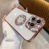 A person's hand is holding a white iPhone 14 Pro Max case with rose gold trim and diamond accents. The case has a decorative ring and a camera module with three lenses. Produktbild-Vorschau