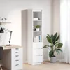 A tall, narrow white bookshelf with drawers and shelves, placed next to a desk with a lamp and a potted plant.