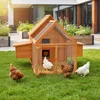 A wooden chicken coop with chickens in a grassy yard in front of a modern house. Podgląd zdjęcia produktu