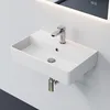A white ceramic wall-mounted sink with a chrome faucet is shown against a light gray wall, with a backlit mirror above. Anteprima dell’immagine prodotto
