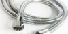 A close-up shot of a silver, flexible metal hose with threaded connectors on both ends, lying on a white surface. Podgląd zdjęcia produktu