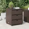 A brown poly rattan cabinet with three drawers sits on a tiled patio, surrounded by lush green foliage. Náhľad obrázku produktu
