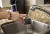 A person is rinsing a coffee pod holder under a faucet in a kitchen sink. Náhľad obrázku produktu