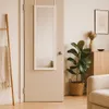 A full-length mirror hanging on a door in a room with a plant and furniture. Anteprima dell’immagine prodotto