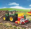 A toy tractor and seeder are shown in a field, with a figure operating the seeder. Anteprima dell’immagine prodotto