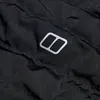 Detailaufnahme des Berghaus Nula Lange Micro Jacket mit reflektierendem Logo auf schwarzem Stoff. Produktbild-Vorschau