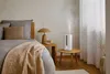 A bedroom scene with a bed, a nightstand, and a humidifier. Náhled obrázku produktu