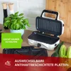 A white and black sandwich maker/grill is open on a kitchen counter, with a plant and vegetables in the background. Overlay text highlights features. Produktbild-Vorschau