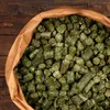 A close-up view of a bag filled with green feed pellets. Produktbild-Vorschau