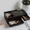A jewelry box with various compartments, displaying jewelry and a watch. Voir les images du produit