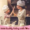 A mother and daughter are baking together in a kitchen, wearing chef hats and aprons. They are high-fiving over a mixing bowl. Anteprima dell’immagine prodotto