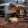 A family is gathered around a table outside their RV, with a diesel heater in the foreground. Voir les images du produit
