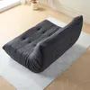 A dark gray tufted sofa is placed on a light gray rug on a wooden floor. Produktbild-Vorschau