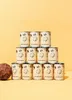 A pyramid stack of 12 cans of coconut milk, with a coconut half in the foreground. Produktbild-Vorschau