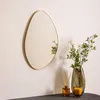 A decorative mirror with a gold frame is displayed on a wall, next to a vase with flowers, a candle, and a diffuser. Náhľad obrázku produktu