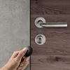 A hand holding a transponder near a door lock and handle. Produktbild-Vorschau