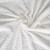 A close-up, swirled view of a cream-colored blanket with a textured chevron pattern. Produktbild-Vorschau