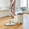 A person is mopping a wooden floor in a living room with a Vitapur mopping system. Podgląd zdjęcia produktu