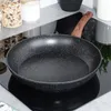 A frying pan with a wooden handle sits on a black induction stovetop. Produktbild-Vorschau