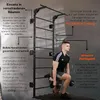 A man is performing a lunge exercise with dumbbells in front of a wall-mounted pull-up bar and ladder. Produktbild-Vorschau