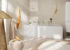A modern bathroom with a freestanding bathtub, a bathrobe hanging on a hook, and a woven floor lamp. Produktbild-Vorschau