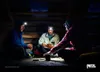 Three people sitting in a dark wooden structure, wearing headlamps and playing cards. Produktbild-Vorschau