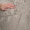 A hand is shown pressing down on a soft, fluffy rug. Produktbild-Vorschau